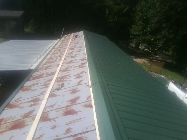 Old rusted panels beside newly installed green metal roofing — Wind Damage Roof Repair by Roofing Brothers in Tavernier