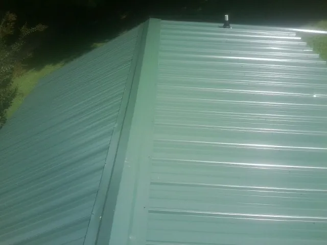 New green metal panels meeting at the ridge of a roof — Flat Roof Repair work by our crew in Tavernier