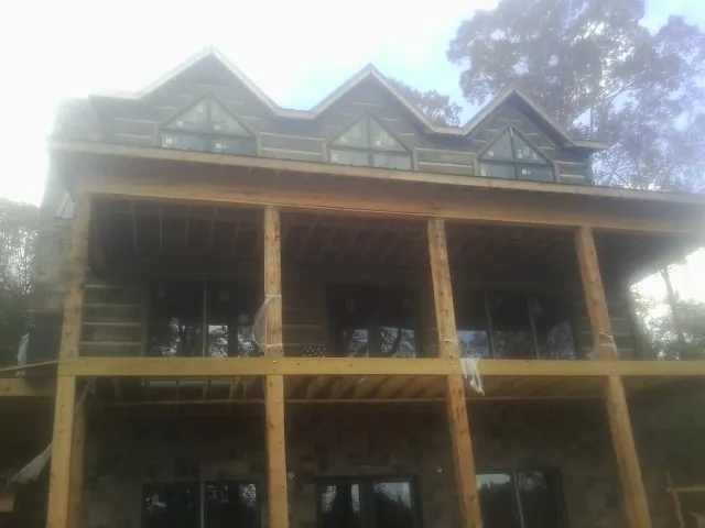 Dormers and porch framing on a large log home under construction — Roof Coating work by our crew in Tavernier
