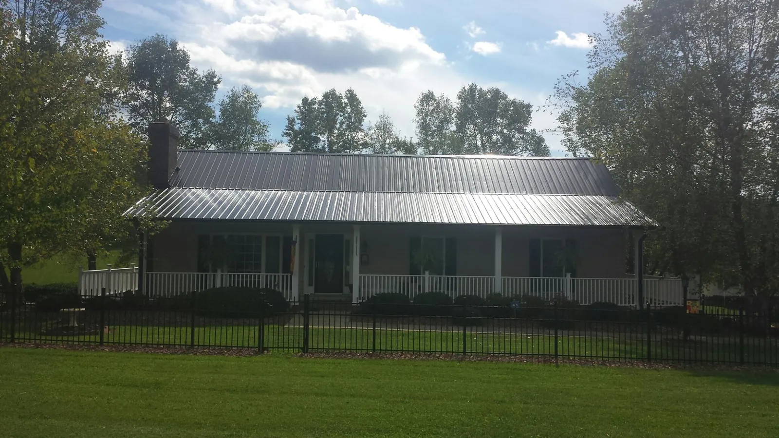 Gray metal roof on a brick ranch with a full width front porch — Gutter Guard Installation work by our crew in Tavernier